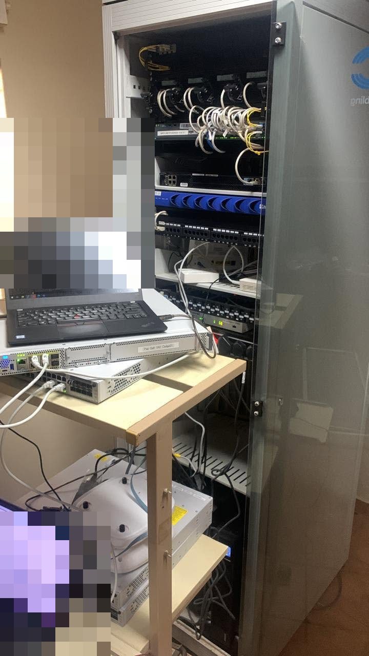 IT Guy Solutions technician laptop in front of an open full-height network cabinet during commissioning