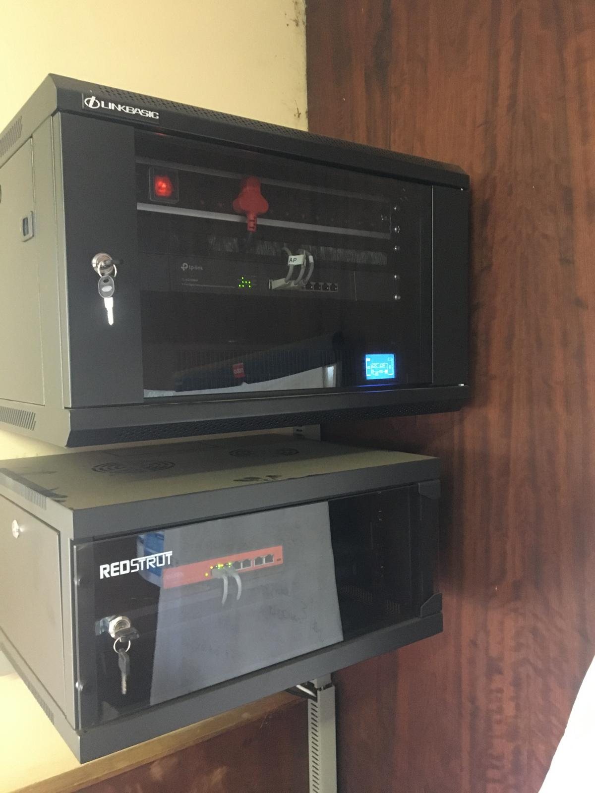 Two locked wall-mounted network cabinets with switching and a firewall