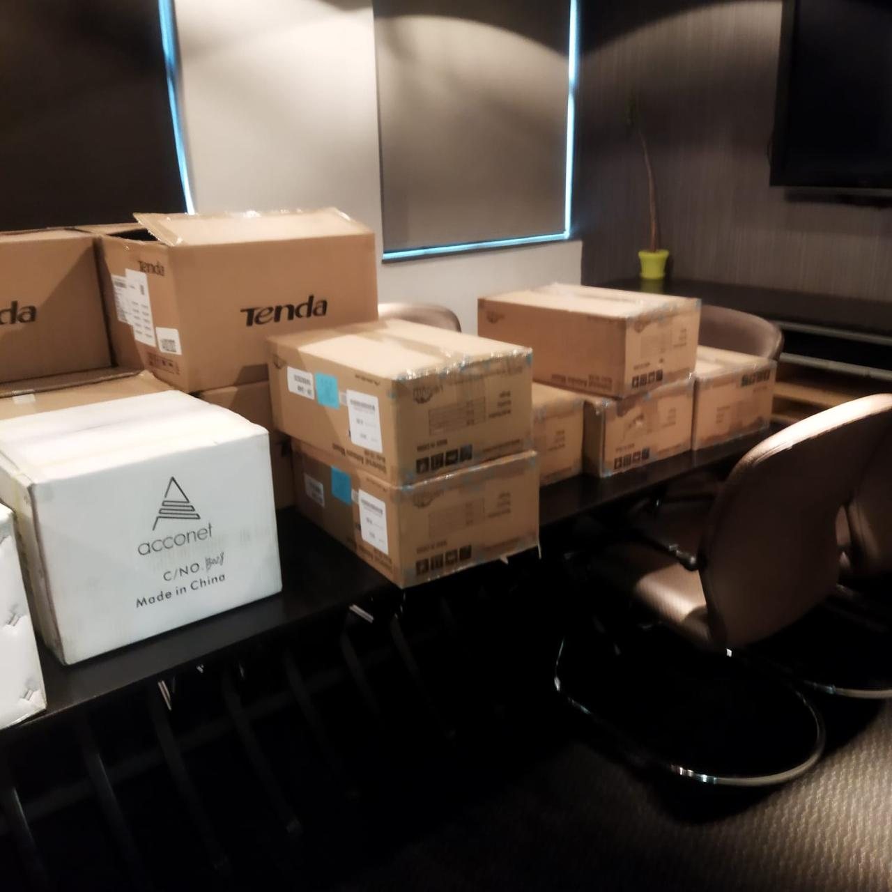 Cartons of access points and network hardware staged on a boardroom table before deployment