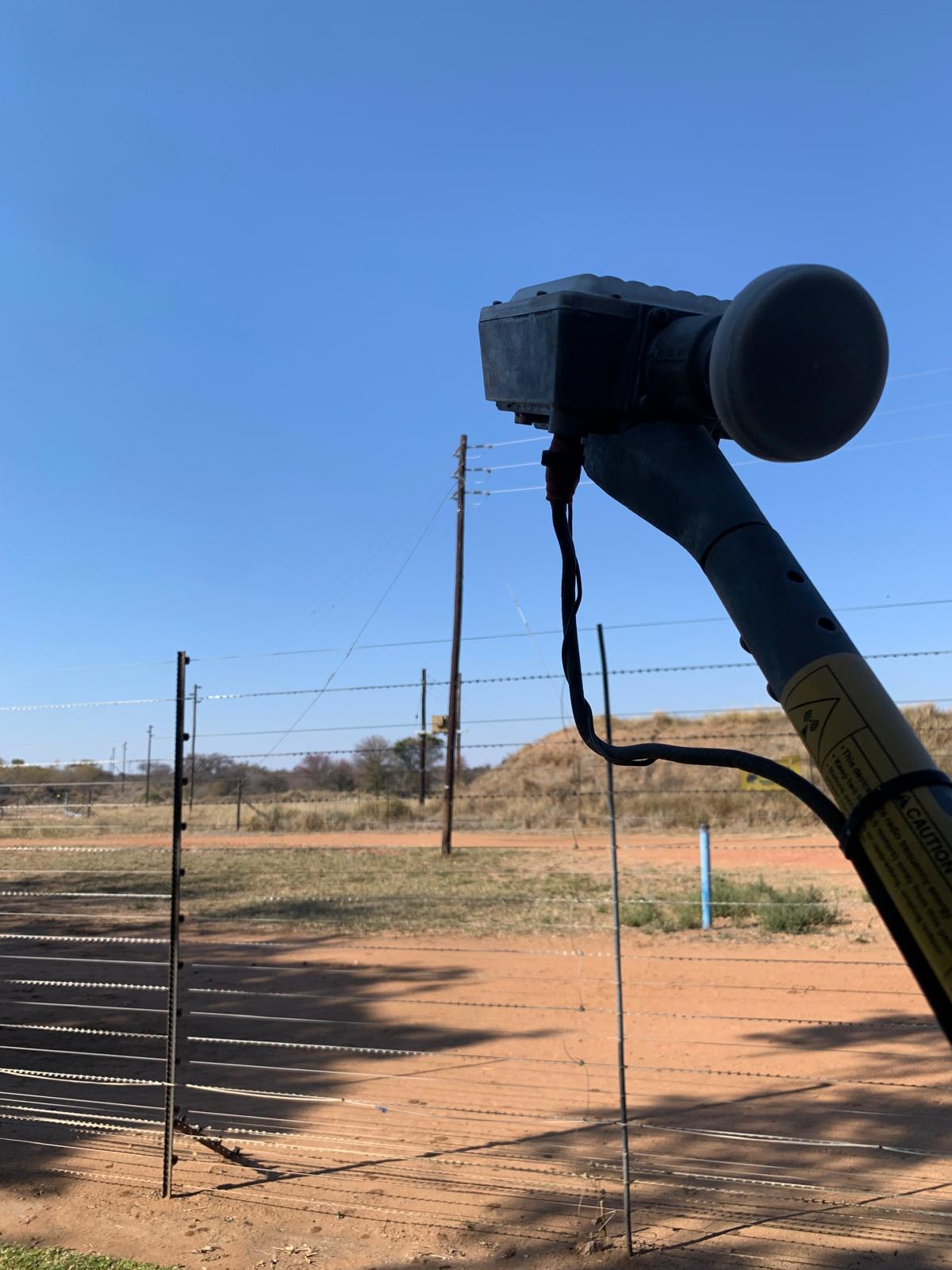 Outdoor radio and dish on a farm fence line under a clear sky