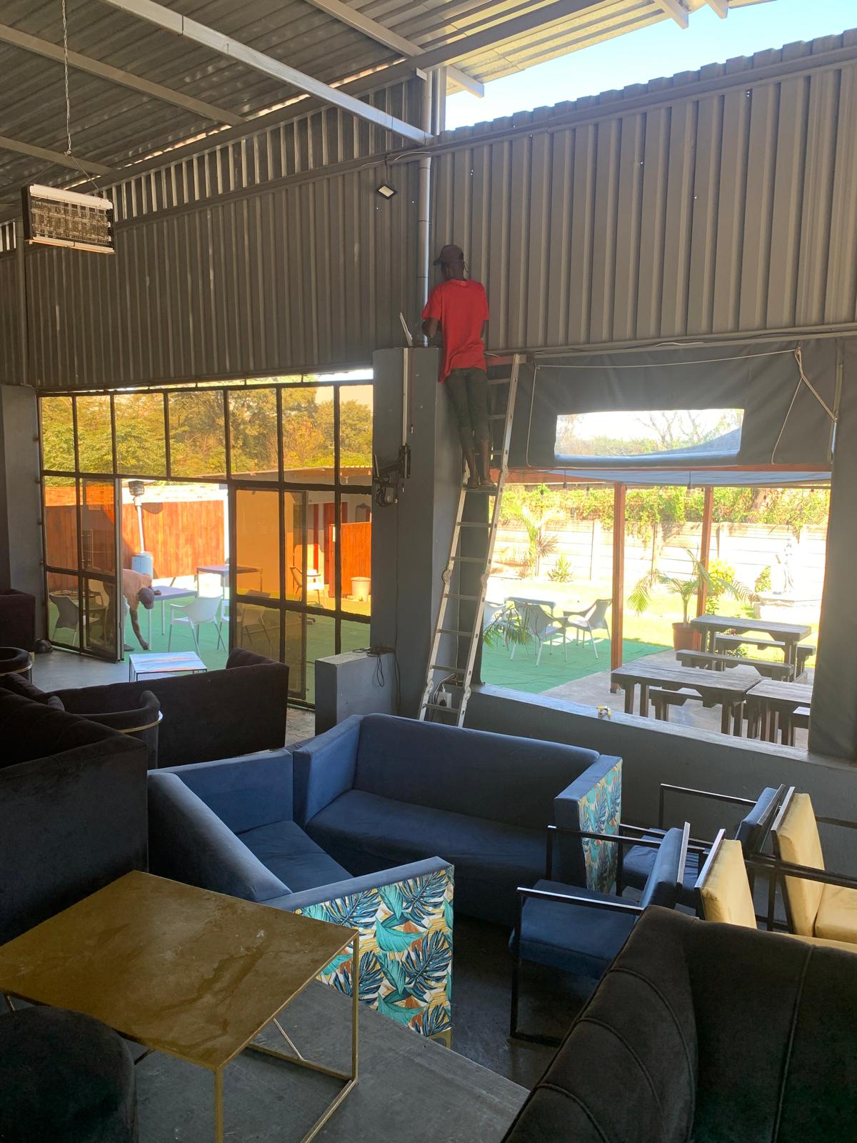 Technician on a ladder installing wireless equipment in a hospitality lounge