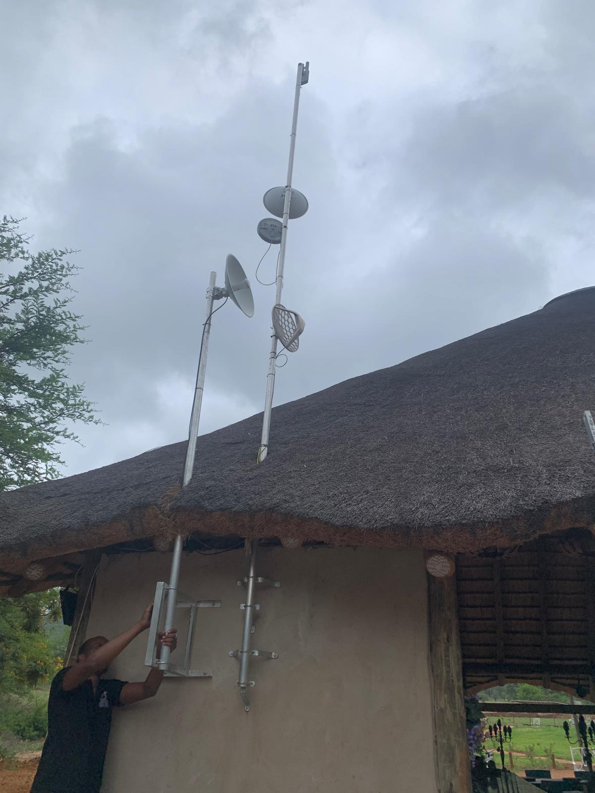 Wireless dishes being mounted on a thatched lodge roof