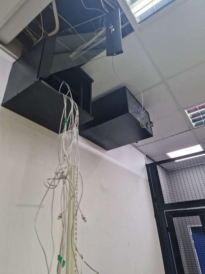 Ceiling-mounted network cabinets with copper drops running down a wall trunking