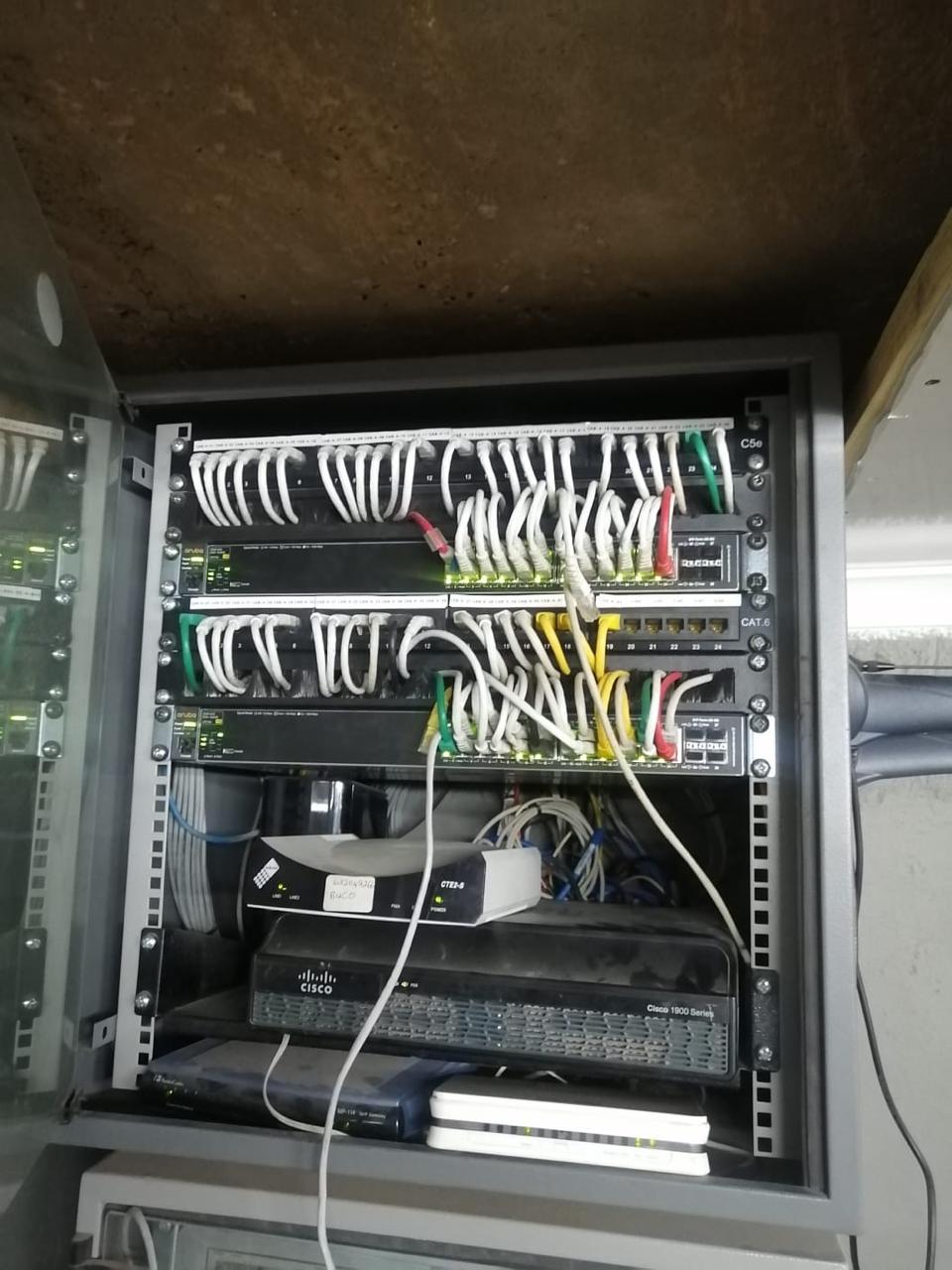 Open wall cabinet showing labelled Cat5e and Cat6 patching into network switches