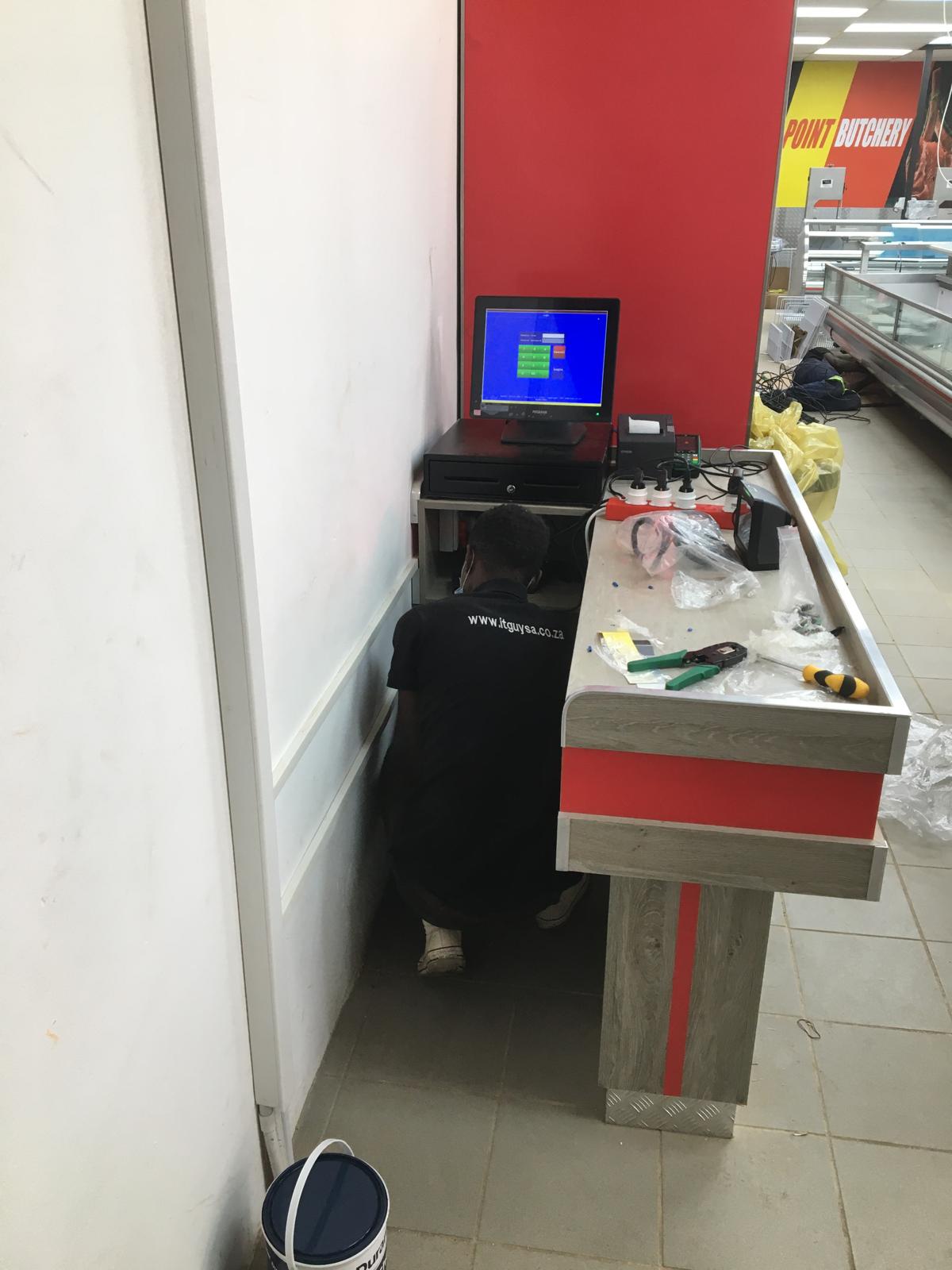 IT Guy Solutions technician installing cabling under a retail point-of-sale counter