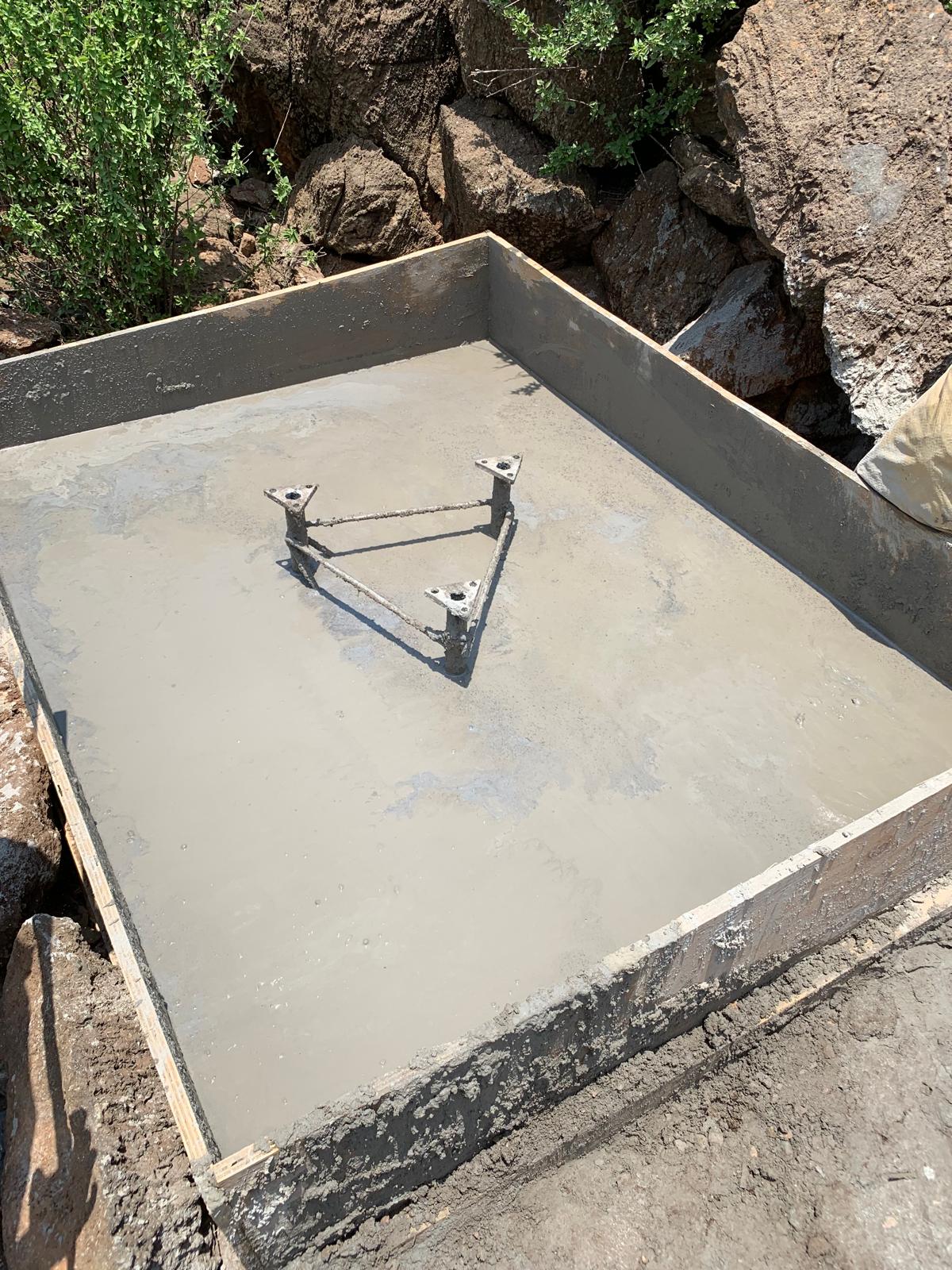 Triangular tower base set in a freshly poured concrete foundation