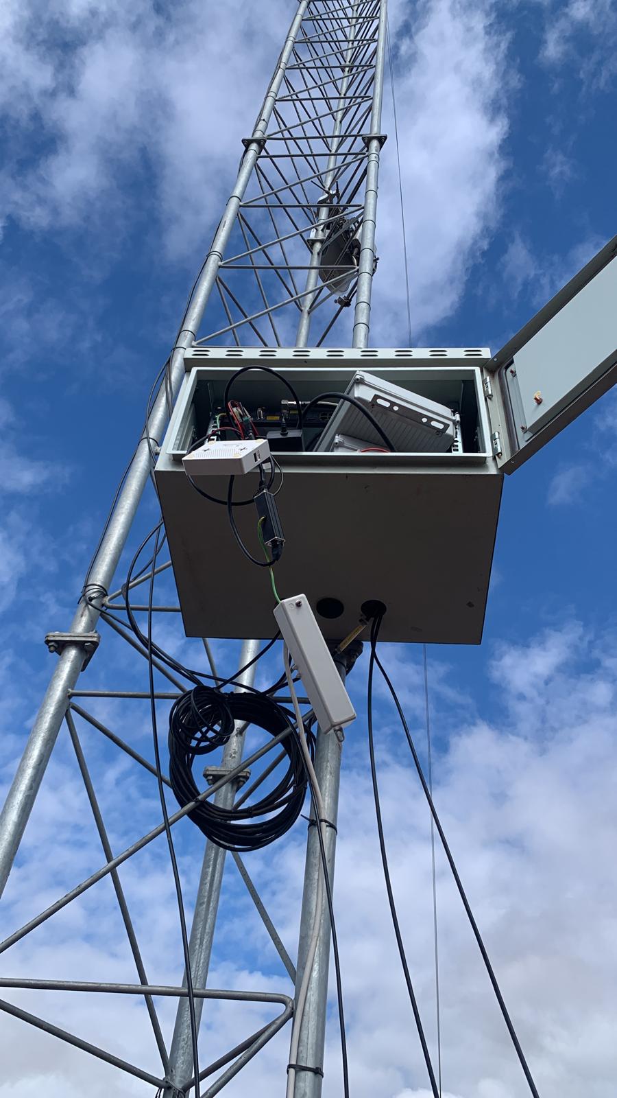 Open radio cabinet mounted on a lattice tower with outdoor wireless equipment inside